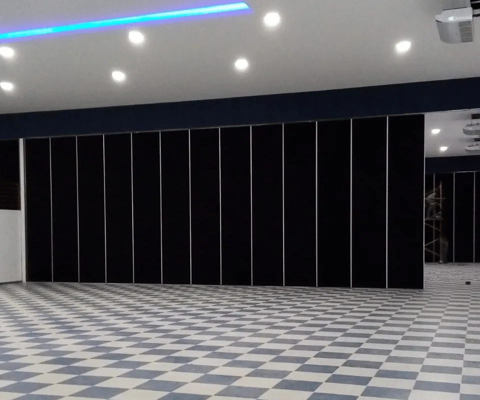Muro móvil Zurbía con acabado en tela negra dividiendo un salón de eventos con piso ajedrezado